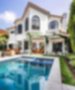 A charming two-story white house, boasting ivy-clad walls and large arched windows beneath a red-tiled roof in Los Angeles.
