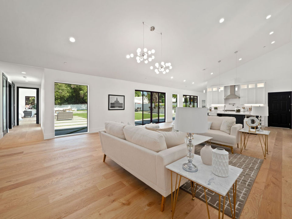 A large and spacious, modern, and bright living room with parquet floors, high ceilings and an open kitchen. 