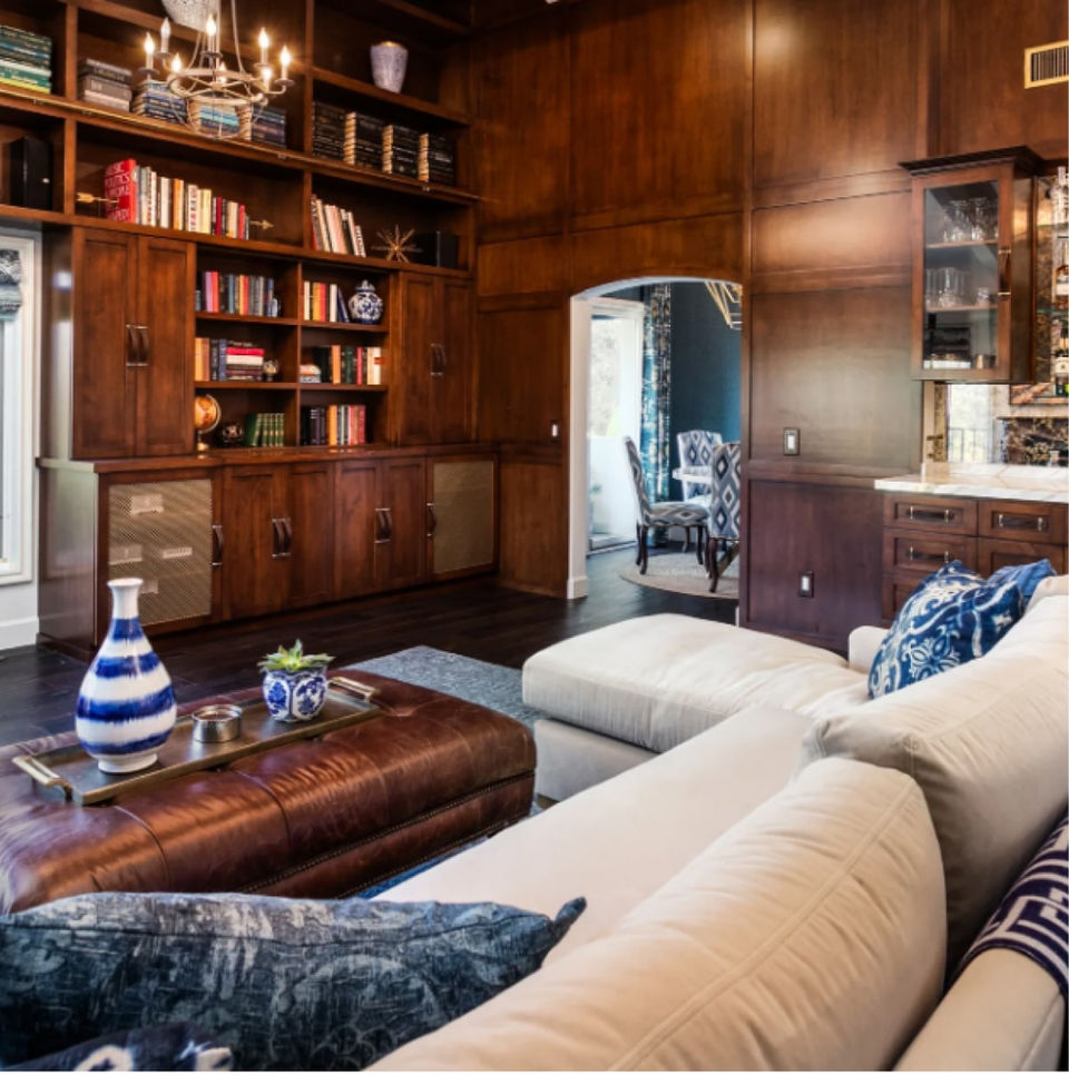 Cozy living room with a white sectional sofa, wooden bookshelves, and a view of a dining room through an archway.