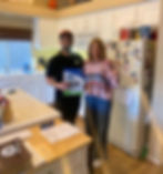 Two people smile in their kitchen, holding a Built to Perfection broschure. The woman gives a thumbs up, celebrating their excitement about their renovation project.
