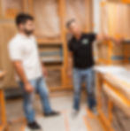 Two men discuss kitchen renovation plans, surrounded by covered cabinets and construction materials, showcasing the craftsmanship of construction company, Built to Perfection.