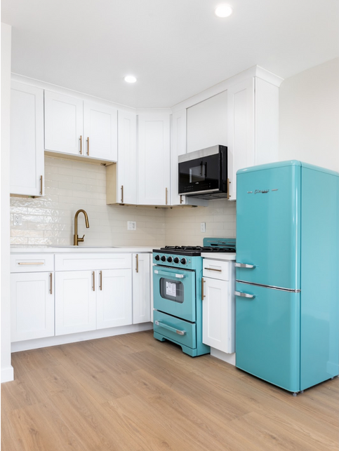 Small kitchen with white cabinets, gold handles, a wood floor and turquoise refrigerator and stove